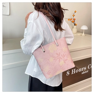 Close-up of pink floral tote bag with silver hardware on model shoulder strap detail