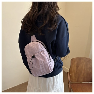 Detail of light purple nylon chest bag featuring drawstring pocket and wrinkled fabric