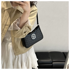 Close-up of black underarm bag featuring all-over 'M' monogram and silver metal logo