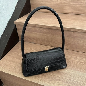 Chic black crocodile pattern baguette underarm bag with gold buckle on wooden background