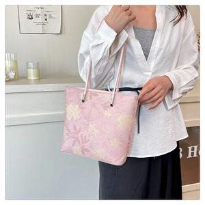 Detail of pink floral tote bag with leather texture and silver hardware on white shirt