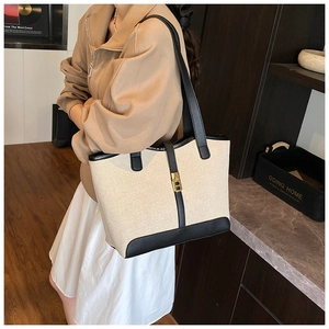 Detail of contrast tote bag with gold metal buckle and black leather shoulder strap