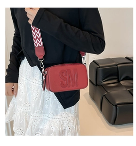 Vue détaillée du sac bandoulière rouge carré avec logo embossé et sangle large