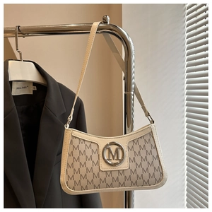 Detail view of beige shoulder bag with M letter prints and silver metal logo on a hanger
