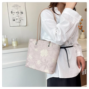 Detailed close-up of dusty pink tote bag with white floral patterns and slender straps