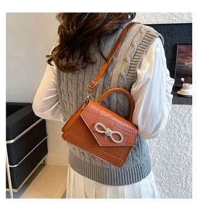 Brown crocodile texture handbag with sparkling silver rhinestone bow detail in profile
