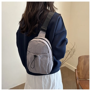 Detail of light grey nylon crossbody bag with adjustable wide strap and drawstring pocket