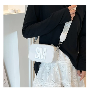 Détail du sac photo blanc bandoulière avec une large sangle tissée aux motifs géométriques