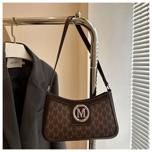Detailed view of brown monogram retro shoulder bag with silver M logo buckle and leather strap