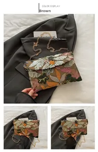Dettaglio del ricamo di paillettes marroni con motivi a foglia sulla borsa a catena