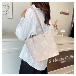 Close-up of floral tote bag with leather strap and silver hardware on female model