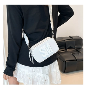 Gros plan sur un sac blanc avec logo en relief et large bandoulière en tissu tissé