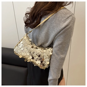 Detail of a gold sequin hobo bag with round metallic texture on a model's shoulder