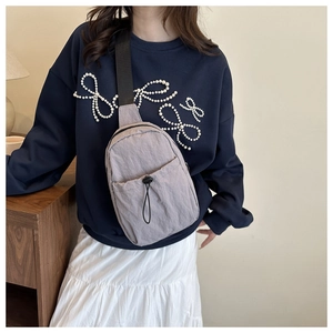 Detail view of light purple nylon crossbody bag with adjustable black shoulder strap
