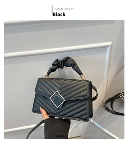 Detailed close-up of a black quilted handbag with a gold geometric lock and pleated handle