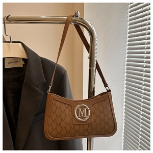 Detailed shot of brown retro underarm bag with M monogram print and silver logo