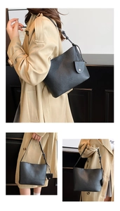Detail of black pebbled leather tote bag with adjustable strap and mini charm