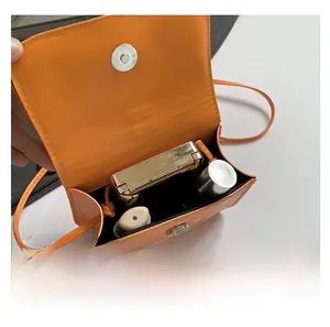 Close-up of orange mini polka dot bag showing capacity for lipstick and compact mirror