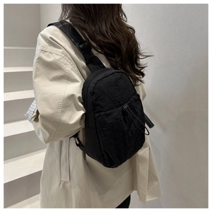 Detail view of a black lightweight nylon crossbody bag featuring an adjustable wide strap