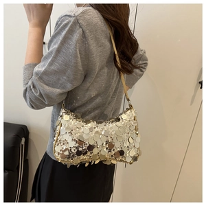 Detail of shimmering silver and gold sequins on a stylish shoulder bag with gold strap