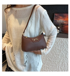 Close-up of brown litchi pattern leather underarm bag with silver metal bow detail