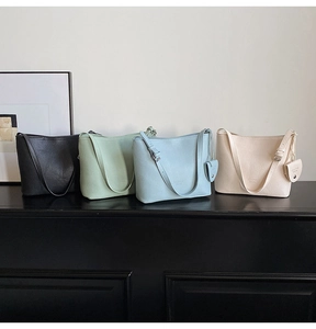 Minimalist bucket bags in black, green, blue, and cream colors with heart charms