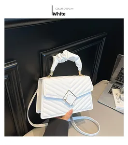 Close-up of white quilted handbag featuring cloud handle and geometric metal clasp