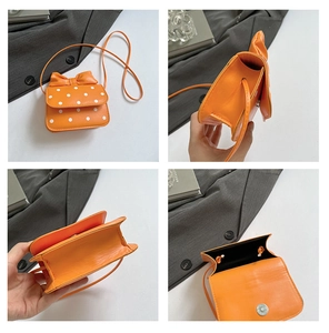 Detail view of orange polka dot mini crossbody bag with bow accent and magnetic closure