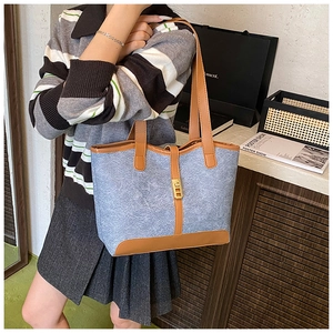 Detail of light blue denim tote with brown leather trim and golden buckle closure