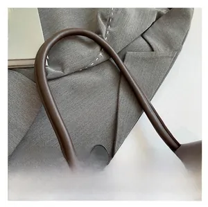Close-up of durable leather handle stitching on a dark brown professional tote bag