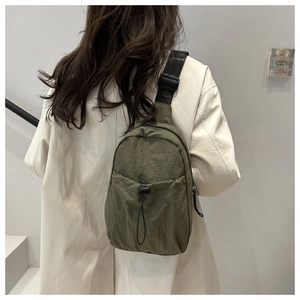 Army green nylon crossbody bag with drawstring pocket and adjustable strap on model