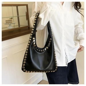 Detail of black leather hobo bag with large silver rivets shown on shoulder