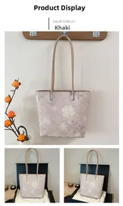 Detail view of khaki floral tote bag with shoulder straps and decorative metal hardware
