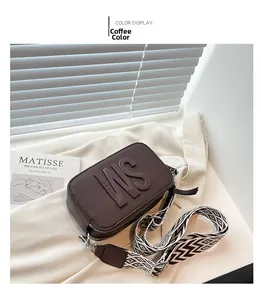 Détail du sac bandoulière marron café avec logo embossé et large sangle tissée