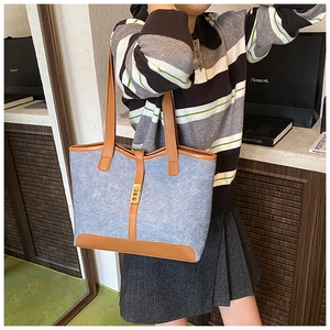 Blue denim and brown leather tote bag with gold buckle shown on a female model