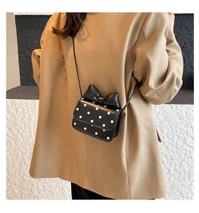 Close-up of a mini black polka dot crossbody bag with a chic 3D bow on the blazer outfit