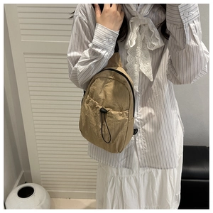 Detail of khaki nylon chest bag with functional drawstring pocket and smooth zipper