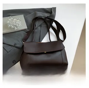 Detailed view of dark brown matte leather crossbody bag with a gold magnetic flap closure