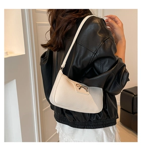 Close-up of cream lychee leather texture and golden bow buckle on hobo underarm bag