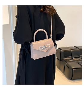 Detail of crocodile embossed crossbody bag featuring a sparkling rhinestone bow detail