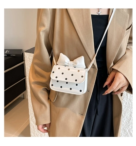Detailed view of polka dot crossbody bag with a large bow on a model outfit