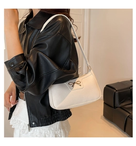 Detail of white lychee leather shoulder bag with elegant golden bow metal hardware