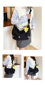 Detail of black nylon tote featuring pink bows and a yellow flower pendant accessory
