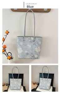 Detail of light blue tote bag with floral print and silver buckles in a gift box