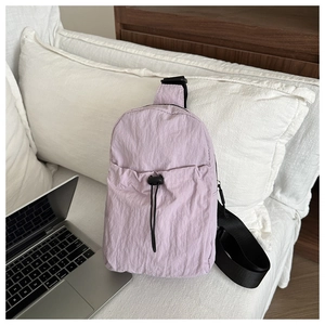 Detail of light purple pleated nylon crossbody bag with drawstring pocket and black strap