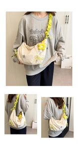 Three-way view of a beige nylon drawstring hobo bag with yellow ruched strap and daisy charm