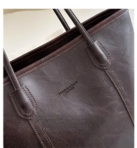 Dettaglio della borsa tote in pelle marrone con grana visibile e cuciture rifinite