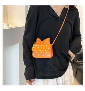 Detail of orange polka dot mini crossbody bag with a bow on a fashion model