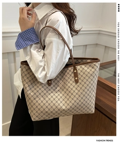 Detailed view of monogram tote bag with brown leather handles and gold rivet hardware