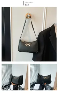 Detail view of black lychee grain shoulder bag with elegant golden bow metal hardware